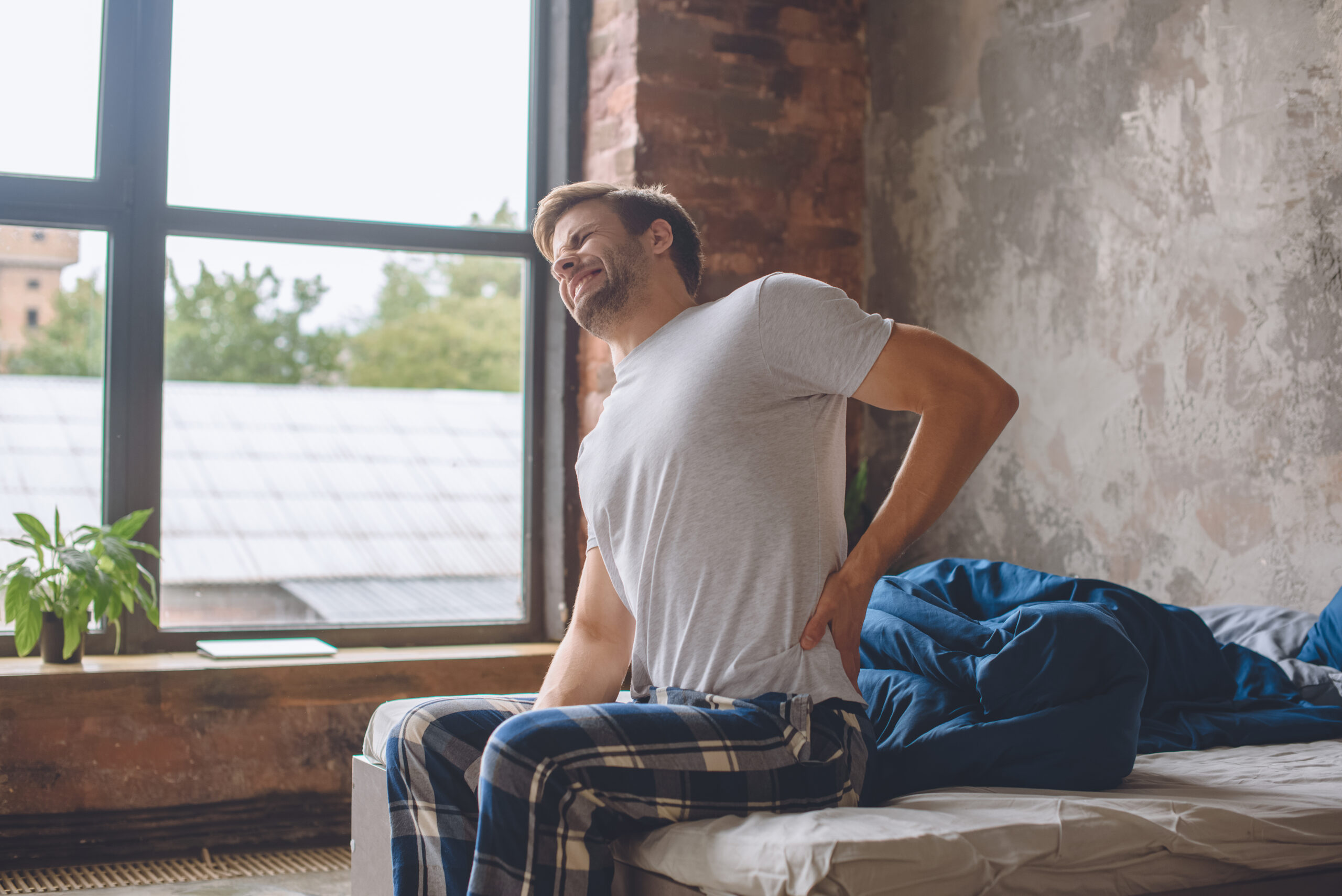 Young man in bed with back pain