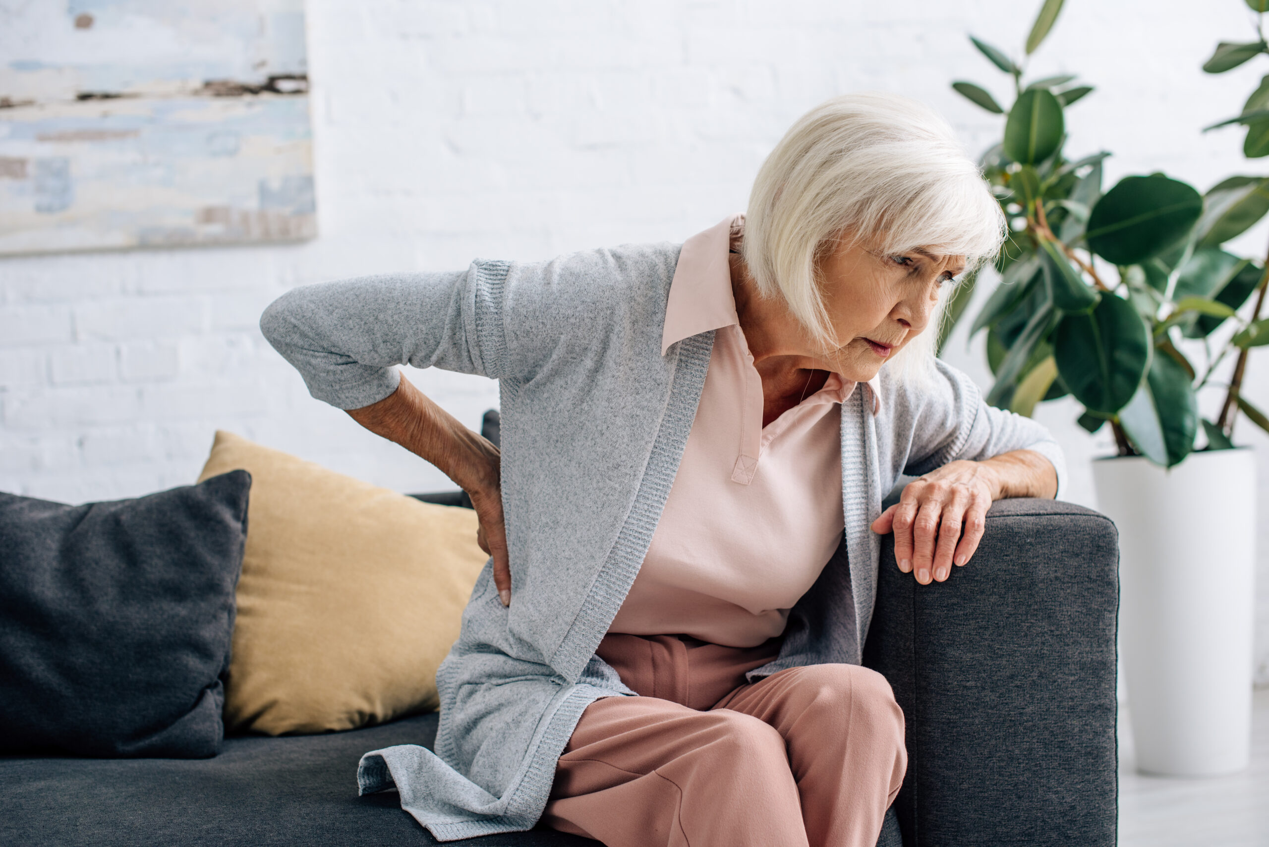 senior women with low back pain getting off the couch