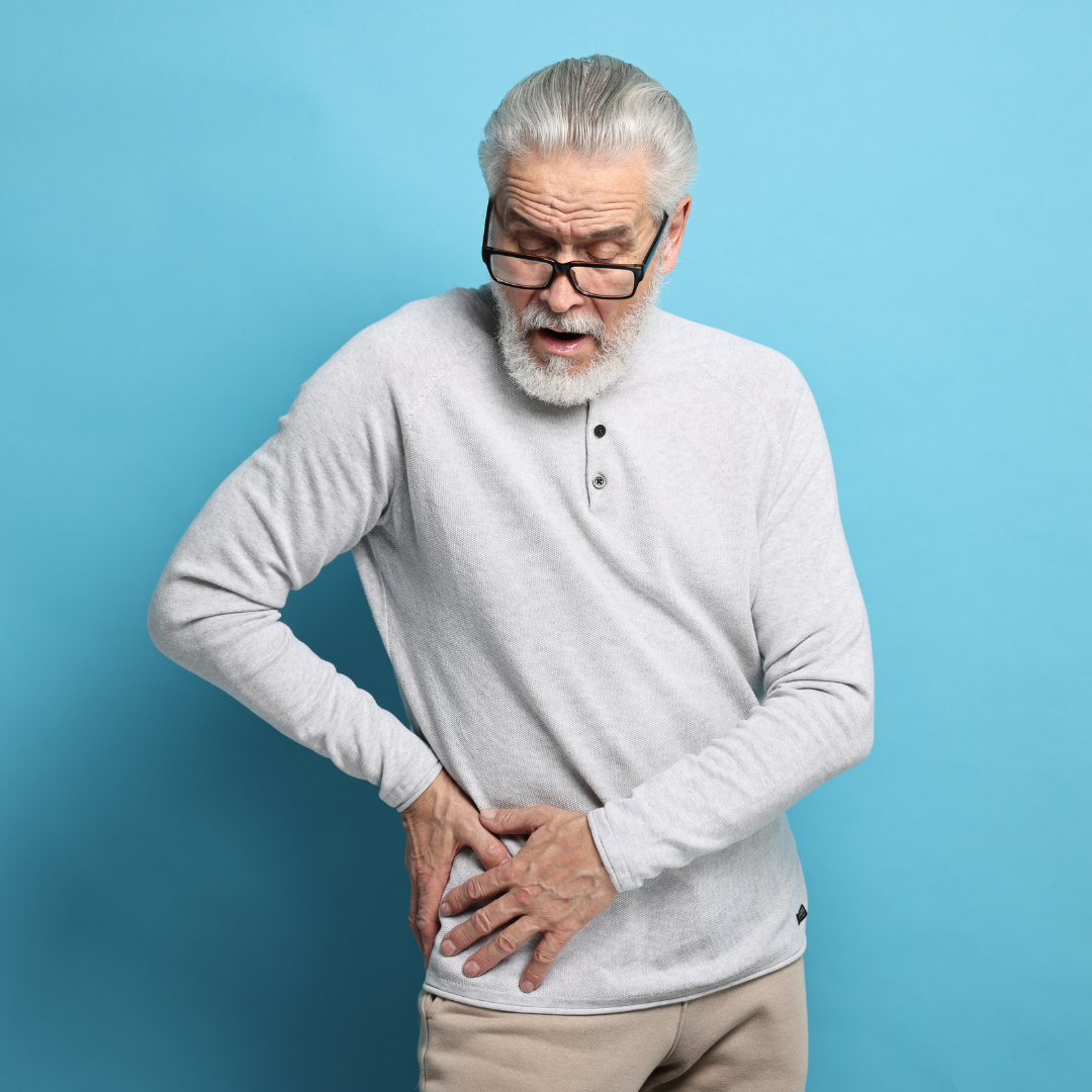 an elderly man standing holding his right hip because of the arthritic hip pain