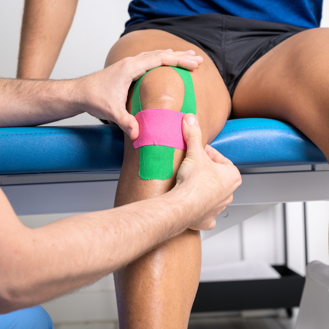 chiropractor placing kinesiotape on an athlete's injured knee