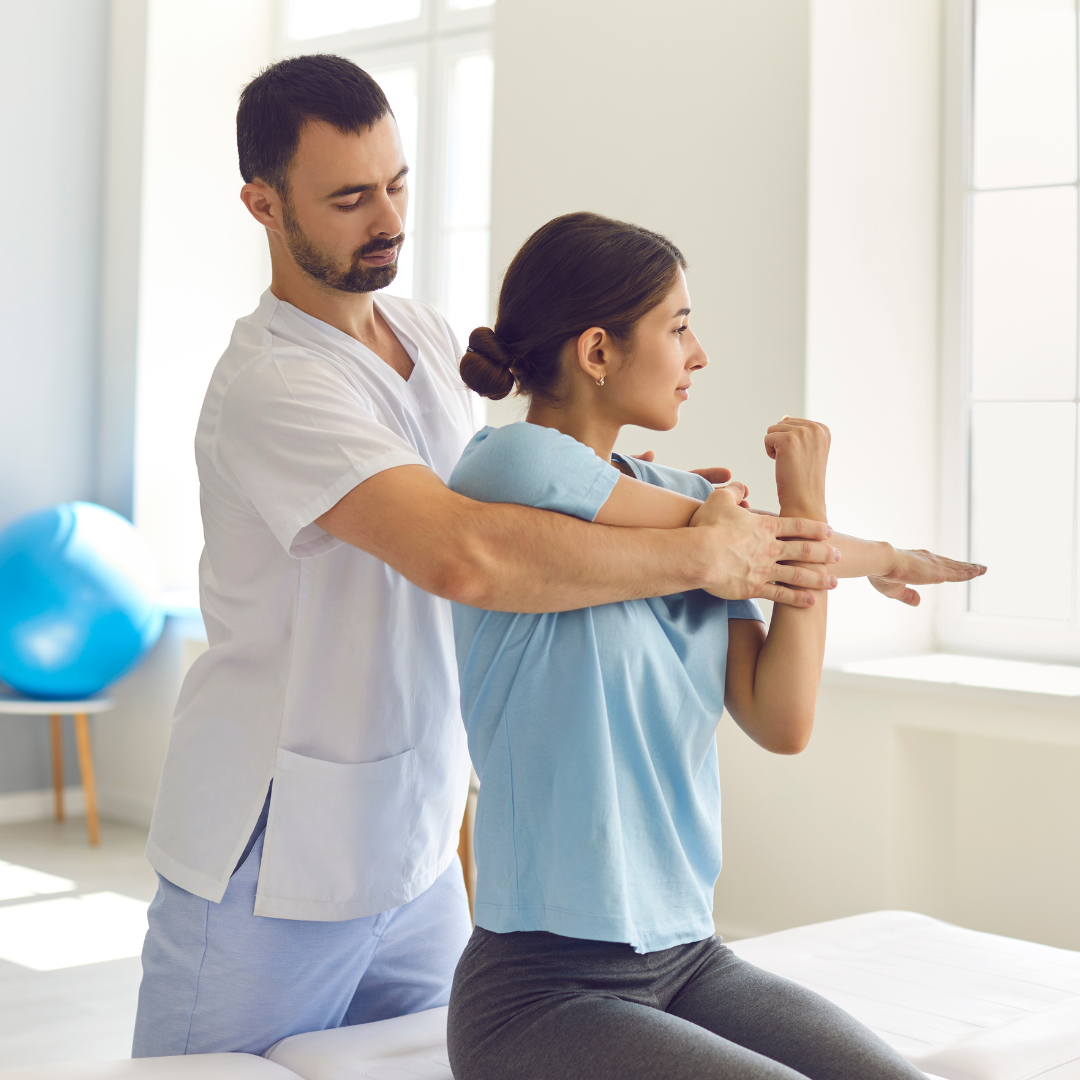 chiropractor standing behind a patient, treating her shoulder and back