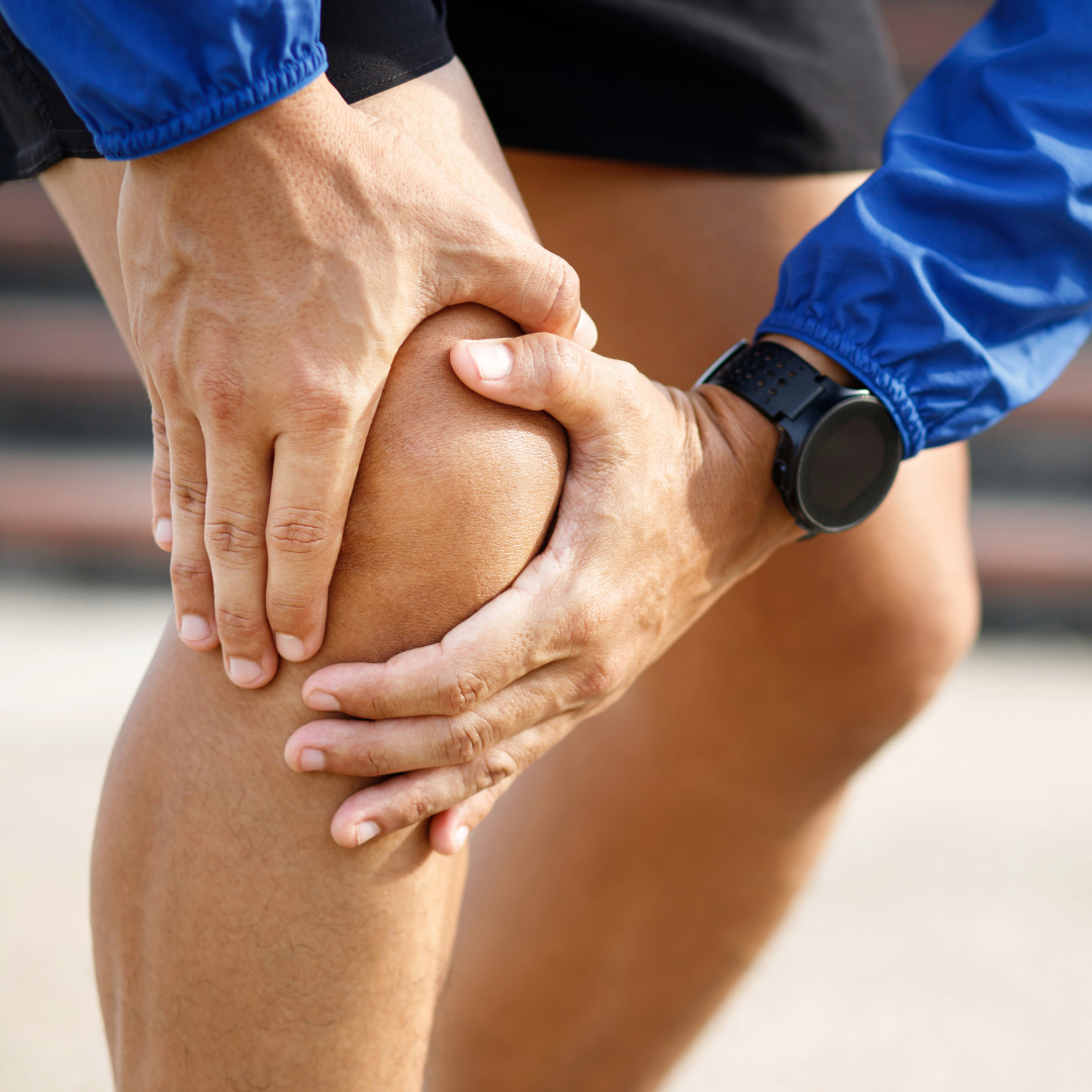 a runner out for a run, holding their knee because of their knee tendonitis acting up