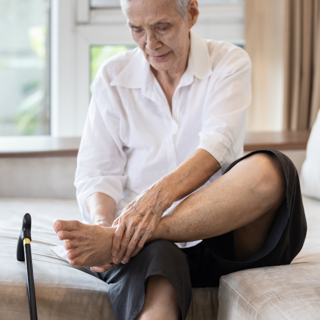 man sitting on bed holding his numb foot and ankle